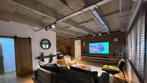Una sala de estar moderna con un televisor de pantalla plana grande, un sofá, una silla y piso de madera.