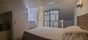 Ein Schlafzimmer mit einem Bett, einem Kleiderschrank, einem Spiegel und einer Raumtrennwand.