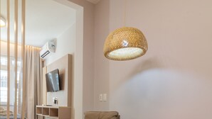 Et moderne værelse med en beige stol, et rundt træbord og en vævet pendel.