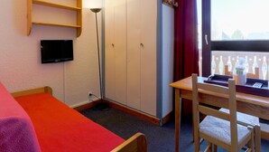 Ein Zimmer mit einem Bett, einem Schreibtisch, einem Stuhl, einem Kleiderschrank, einem Fernseher und einem Fenster mit Blick.