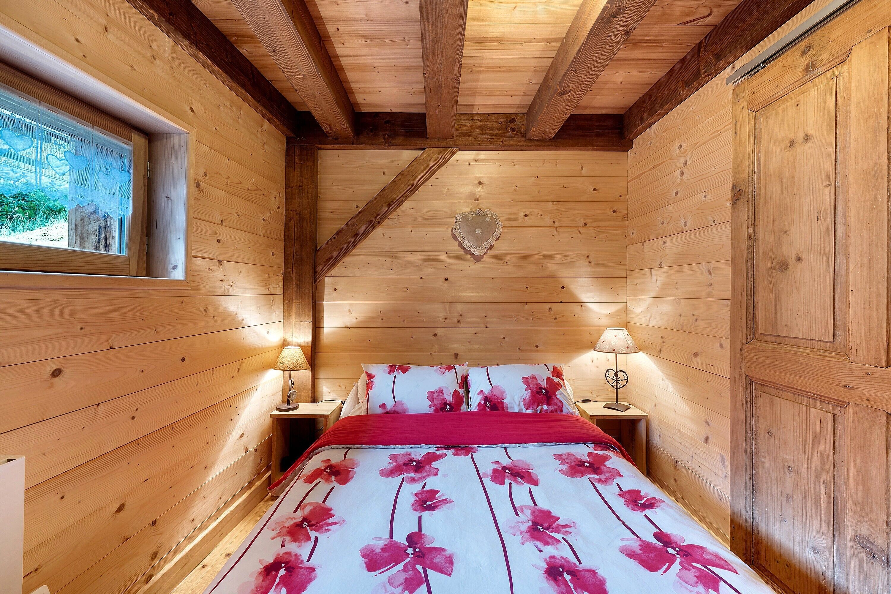 Una stanza in legno con un letto, due comodini e una finestra.