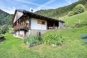 A rustic mountain house with a wooden balcony, stone foundation, and a garden with various plants. - Bed and Breakfast 'Chambre D'hôte Dans Chalet D'Alpage' with Mountain View, Private Terrace and Private Garden (Beaufort)