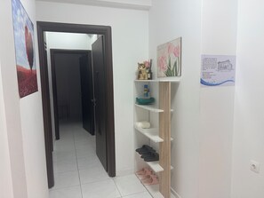 Ein Flur mit einer Holztür, einem Regal mit Hausschuhen und einem gerahmten Bild an der Wand.