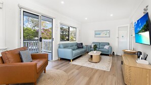 Ein Wohnzimmer mit einem braunen Ledersofa, einem blauen Sofa, einem Couchtisch und einem Fernseher an der Wand.
