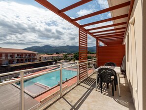 Un balcón con piscina, mobiliario exterior y vistas a las montañas.