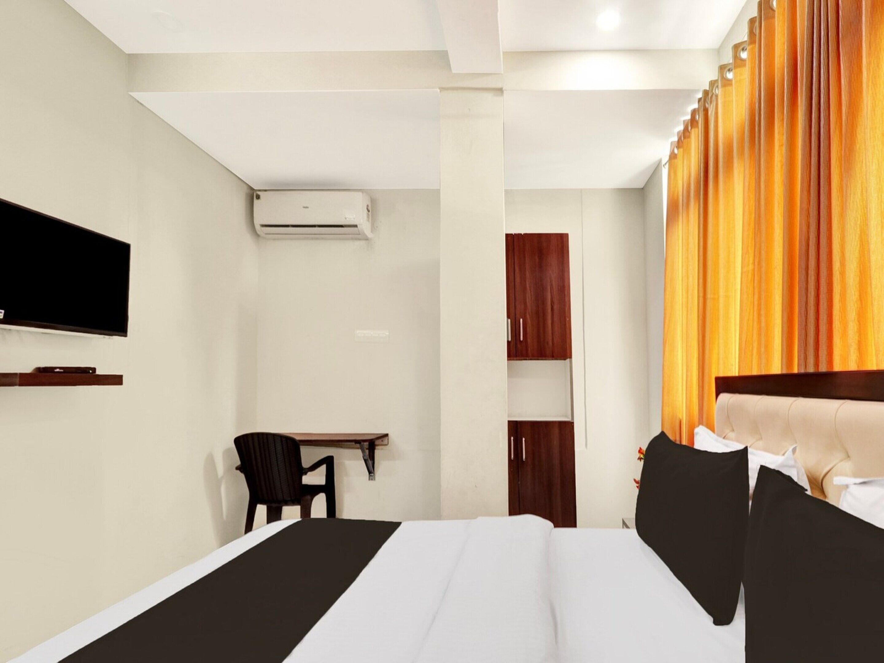 A hotel room with a bed, a TV mounted on the wall, a desk, and a wardrobe.
