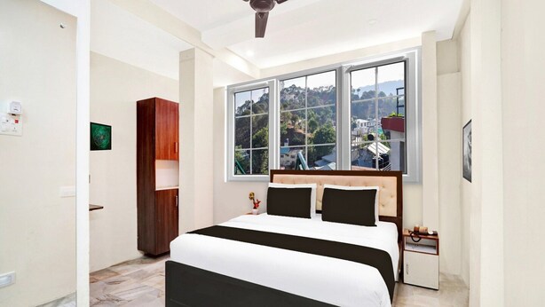 Un dormitorio con cama, ventana con vistas, ventilador de techo y armario de madera.