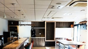 A modern kitchen with wooden countertops, bar stools, and pendant lighting. - 6-person Wooden Chalet in Correze (Meyrignac-l'Eglise)