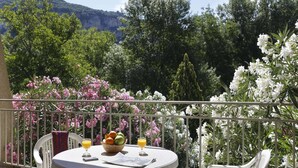 A balcony with a table, chairs, a fruit bowl, and glasses of juice. - Studio in the Heart of Nature (Vallon-Pont-d'Arc)