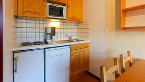 A compact kitchen with wooden cabinets, a microwave, a coffee maker, and a dishwasher. - Studio in Les Deux Alpes With Balcony (Les Deux Alpes)