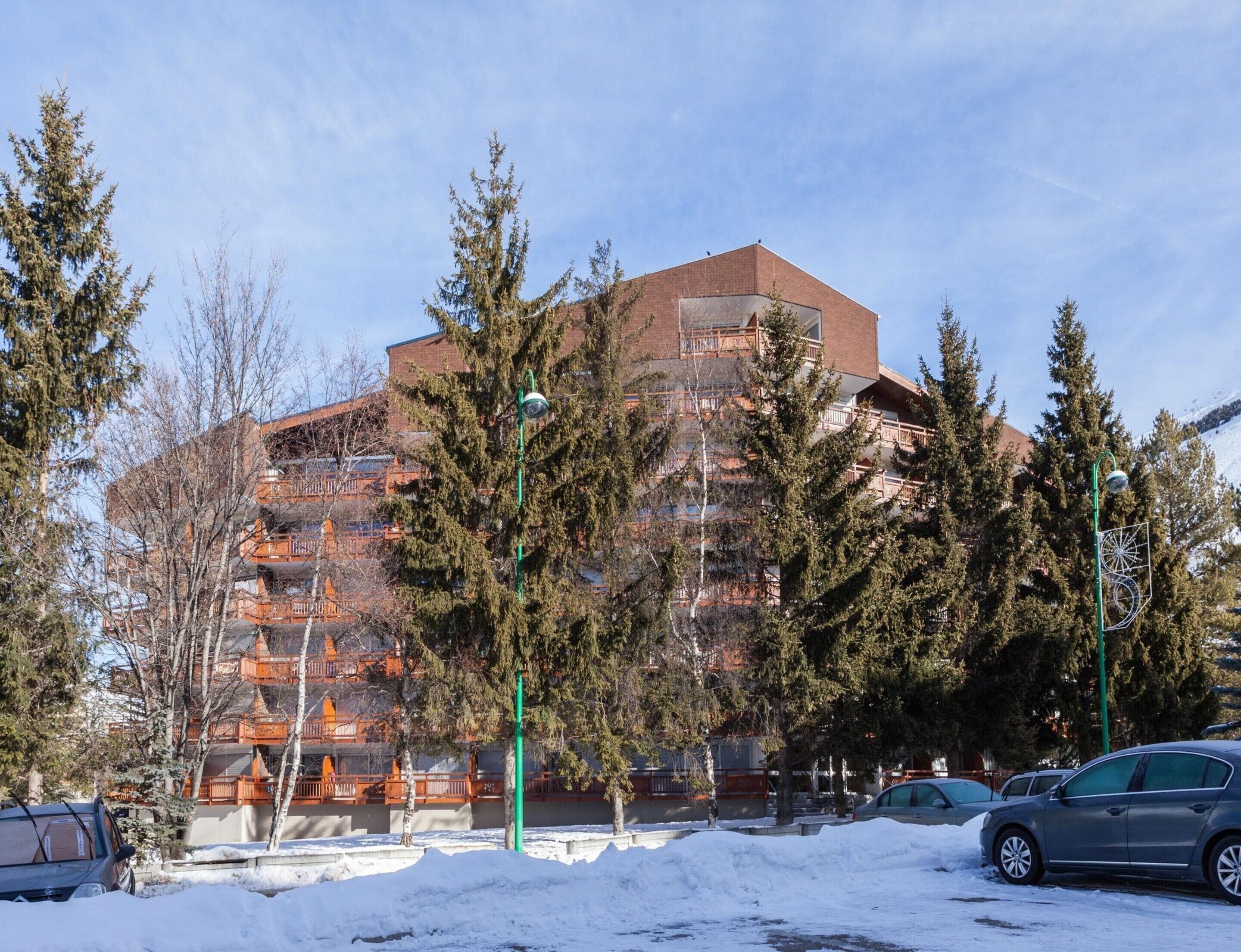 A multi-story building with a brick facade, surrounded by snow-covered ground and trees.