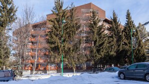 A multi-story building with a brick facade, surrounded by snow-covered ground and trees. - Studio in Les Deux Alpes With Balcony (Les Deux Alpes)