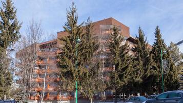 A multi-story building with a brick facade, surrounded by snow-covered ground and trees.
