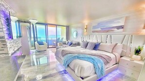 Een moderne slaapkamer met een groot bed, een glazen wand en uitzicht op de oceaan.