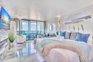 A modern hotel room with a large bed, a balcony with a view, a seating area, and a large painting. - WOW Miami Themed Luxurious Direct Oceanfront Condo (Myrtle Beach)
