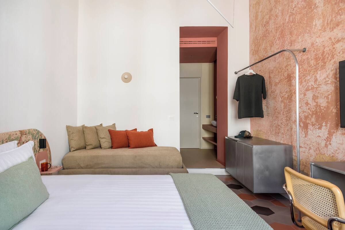 Une chambre à coucher avec un lit, un canapé, un bureau et une chaise.