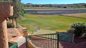 Vistes d'un camp de golf sota un cel clar, amb una serralada de muntanyes al capdamunt i una zona residencial en segon pla.