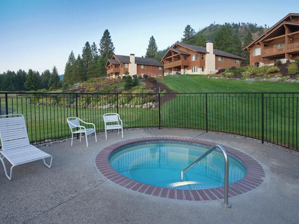 Un espace piscine avec des chaises longues, un jacuzzi et une vue sur les chalets.