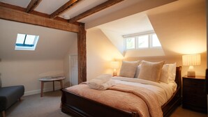 Een slaapkamer met een houten bed, twee bedlampen, een klein rond tafeltje en een raam.