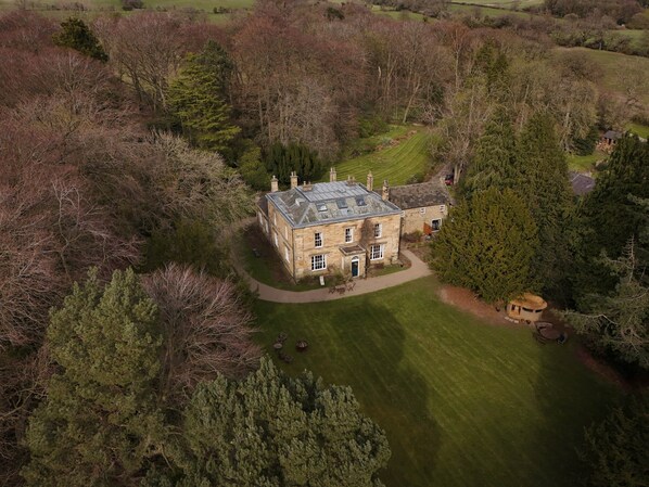 An aerial view of a stone house with a well-maintained lawn and surrounding trees. - The Hall at Burnhopeside Hall Estate (Lanchester)