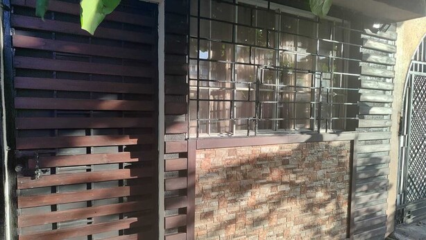 A gated entrance with a metal gate and a brick wall. - WLC Stay (Ayutuxtepeque)