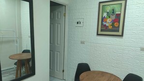 A room with a white textured wall, a framed painting, a wooden table, and black chairs. - WLC Stay (Ayutuxtepeque)