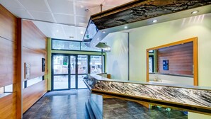 Ein modernes Interieur mit einer Marmor-Rezeption, Holzvertäfelung und einer Decke mit einem perforierten Design.
