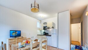 Ein kompakter Wohnbereich mit Essbereich, Küchenzeile und einer Couch mit Blumenmuster.