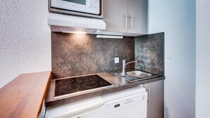 Una cucina compatta con microonde, fornello, lavello ed elettrodomestici.
