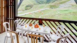 Zona pranzo con tavolo apparecchiato per la colazione, con vista su un paesaggio montuoso e dei binari ferroviari.