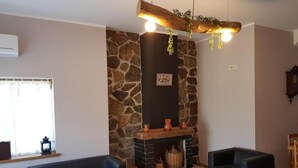 Ein Wohnzimmer mit Kamin aus Stein, zwei Sofas, einem Holztisch und einer Hängeleuchte.