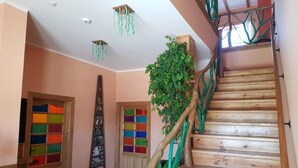 Eine Holztreppe mit grüner Geländer, eine Holztür mit farbenfrohen Feldern und ein an der Wand befestigtes Regal.