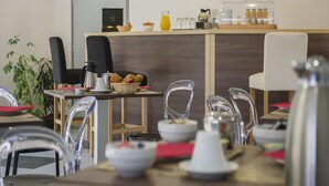 A modern cafe with clear glass chairs, a counter with breakfast items, and pendant lighting. - Stay Near Prehistoric Sites (Les Eyzies)