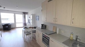 A modern kitchen with a dining area, large windows, and a view of the outdoors. - Baltic Sea vacation apartment K105 (Schönberg)