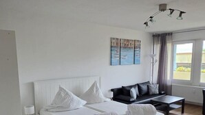 A bedroom with a bed, a sofa, a small table, and a painting on the wall. - Baltic Sea vacation apartment K105 (Schönberg)