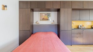 Une chambre comprenant un lit, un petit bureau et un coin cuisine.