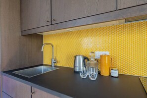 A kitchen with a modern faucet, a kettle, a coffee pot, and a yellow tiled backsplash. - Close to the Castle- Soothing and calm garden view (Versailles)