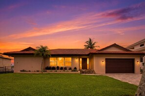 A single-story house with a red-tiled roof, a front garage, and a well-maintained lawn.