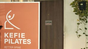 Naamplaatje voor Kefi Pilates Studio, een deur met een 'OPEN' bordje en een stoel.