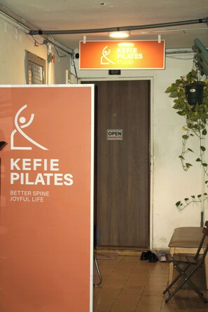 Kefi Pilates -studiota osoittava kyltti, ovi, jossa on kyltti, jossa lukee ”AVOIN”, ja tuoli.