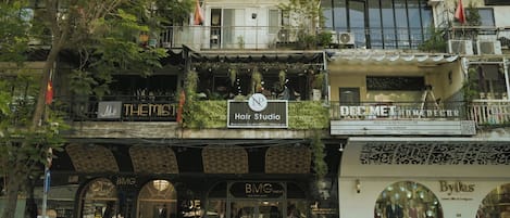 A multi-story building with various shops on the ground floor, including a hair salon and a boutique.