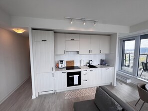 A modern kitchen with white cabinets, a built-in oven, and a window overlooking a cityscape. - 2bedroom,2 bathroom apartment in the heart of Toronto (Toronto)