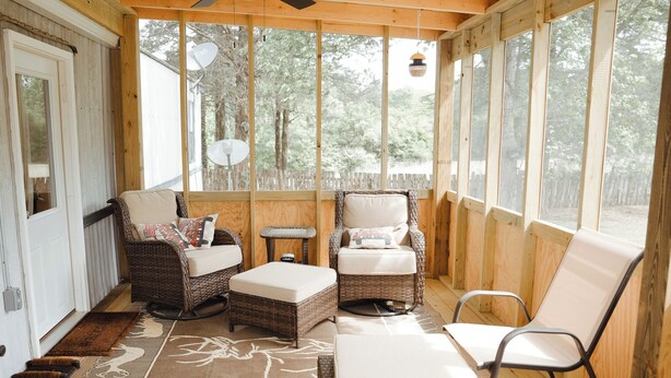 Une véranda couverte, aménagée avec des meubles en osier, une petite table et une chaise.