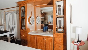 Une cuisine en bois, avec des placards, un plan de travail et un coin repas comprenant une table et des chaises.
