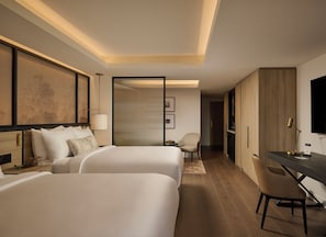 A hotel room with two beds, a desk, a chair, a television, and a sliding door leading to a bathroom. - Glenhill Hotel (Toronto)