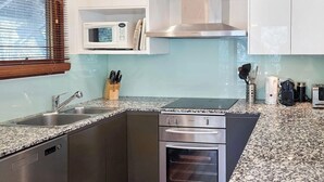 Een keuken met een granieten aanrecht, roestvrijstalen apparatuur en een magnetron aan de wand.