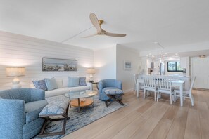 A modern living room with a sofa, armchairs, a coffee table, and a dining area with chairs and a table. - Carlos Pointe #126 - Endless Beach (Fort Myers Beach)