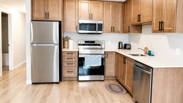 A modern kitchen with wooden cabinets, stainless steel appliances, and a white countertop.