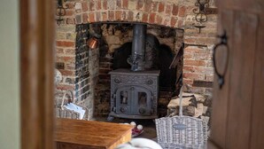 Une pièce rustique avec une cheminée en briques, un poêle à bois traditionnel et des meubles en osier.
