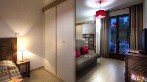 Una camera d'albergo con un letto, un divano, una TV, una scrivania e un balcone con vista.